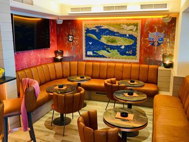 Sitzecke in der Cafe Bar Marinaclub mit Eckbank, Ledersesseln und runden Tischen